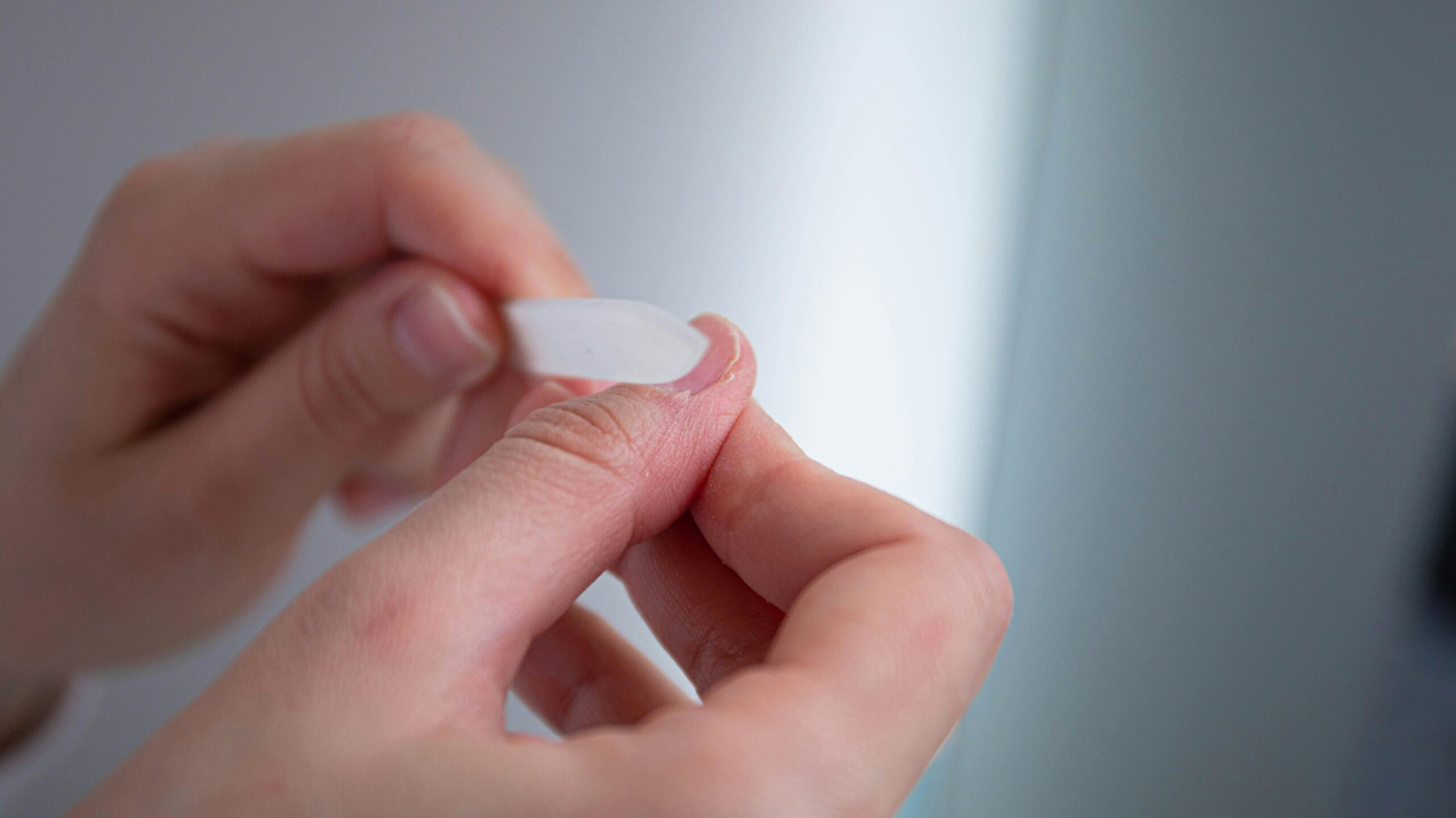 A detailed view of hands using a nail file for grooming purposes.
